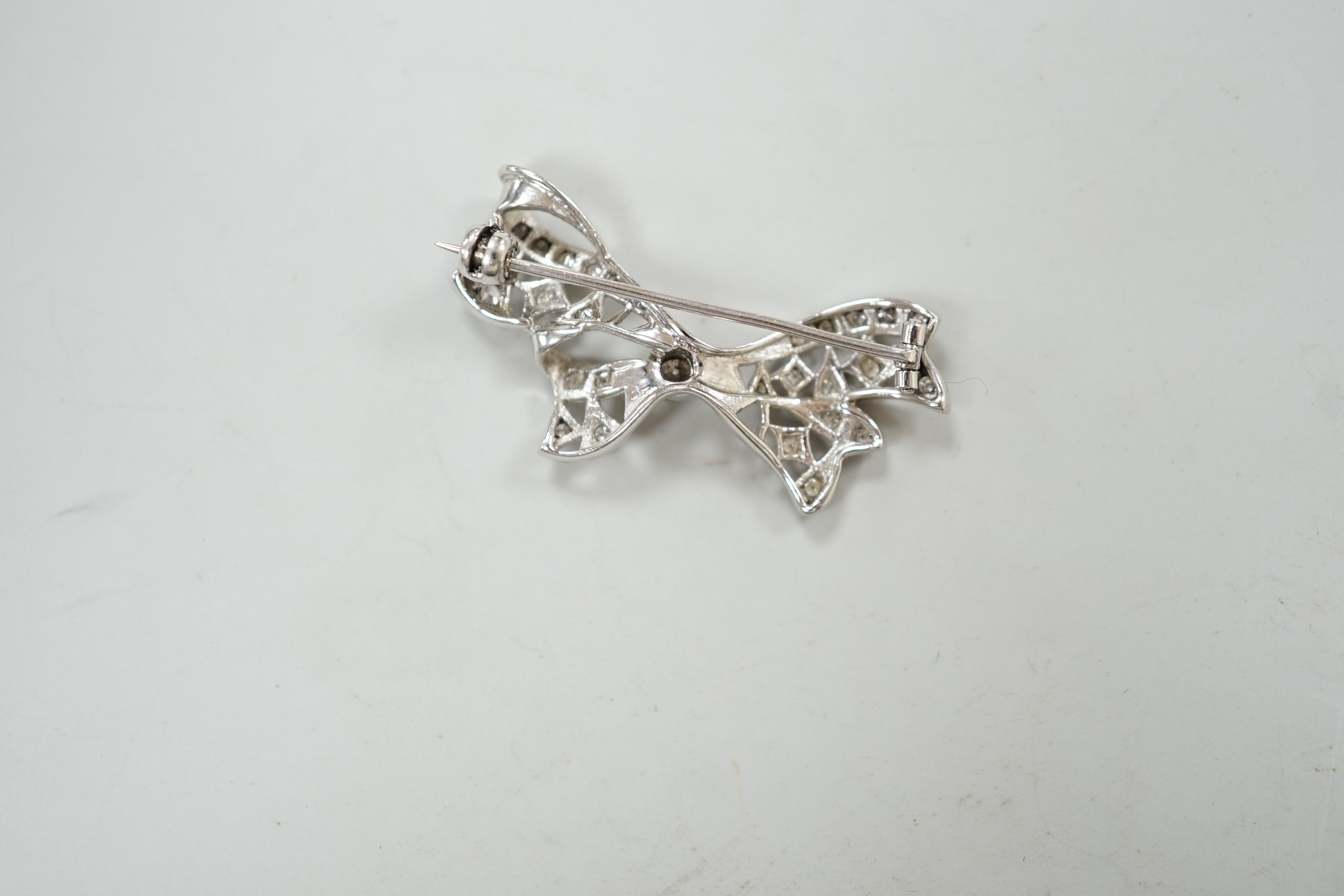 A white metal and diamond cluster set ribbon bow brooch, 36mm, gross weight 4 grams.